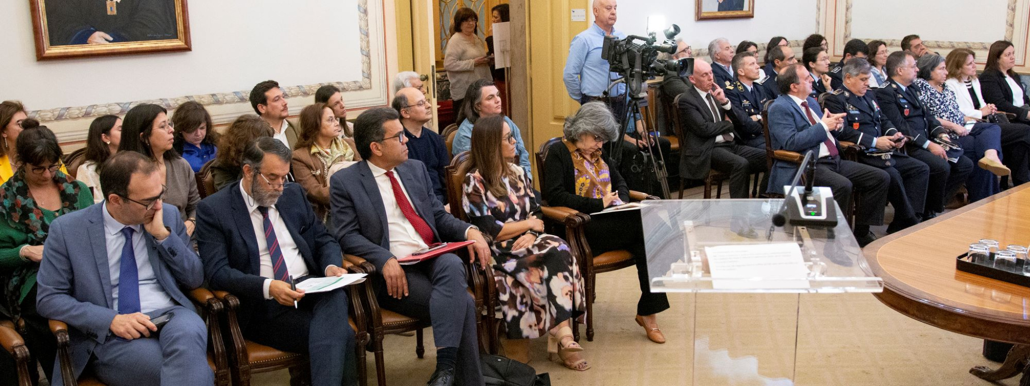 Sala com pessoas a assistir a conferência